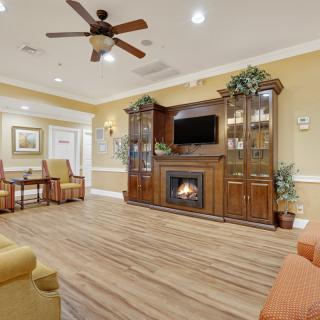 A cozy living room with a fireplace, wooden entertainment center, and ceiling fan.