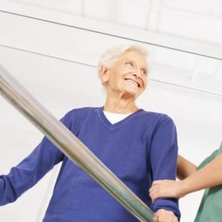 An elderly person receiving assistance while walking down a corridor.