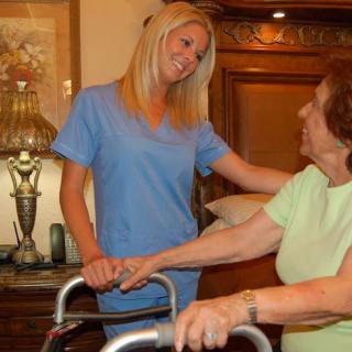 A caregiver assisting an elderly woman using a walker.