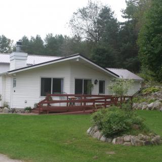 A cozy house surrounded by lush greenery and a well-maintained lawn.