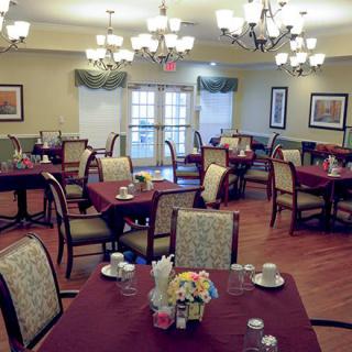 A well-lit dining room with neatly arranged tables and chairs in a formal setting.