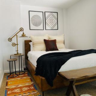 A modern bedroom with minimalist decor featuring a stylish bed, geometric wall art, and a cozy rug.