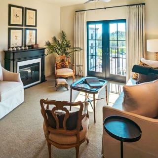 A cozy living room with elegant furniture and a fireplace, illuminated by natural light from French doors.