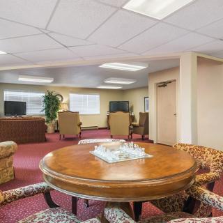 A spacious interior living room with a central round table surrounded by chairs, sofas, and a television.