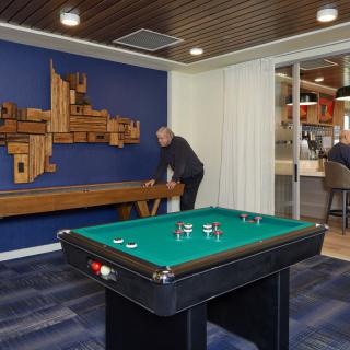 A modern game room featuring a pool table and shuffleboard with stylish interior design.