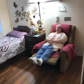 A person sitting comfortably in a chair in a cozy bedroom setting.