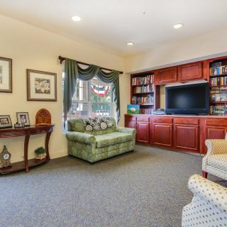 A cozy living room with a green armchair, built-in bookshelves, and a flat-screen TV.