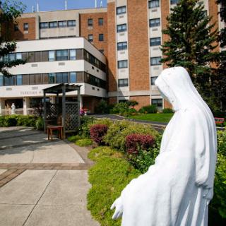 A serene statue stands in the garden of a hospital, providing a moment of reflection.