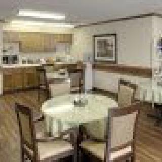 A cozy dining area with round tables and chairs near a kitchen.