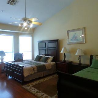 A spacious bedroom with two beds, large windows, and classic wooden furniture.