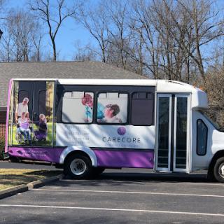 A shuttle bus parked in a lot, decorated with images of people enjoying activities.