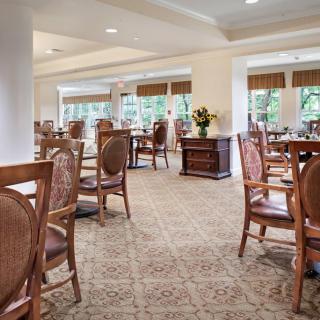 A well-lit dining area with elegant wooden furniture and large windows.