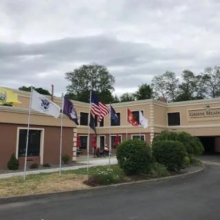 A building exterior with multiple flags displayed out front under a cloudy sky.