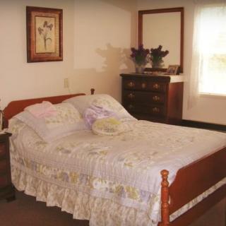 A cozy bedroom with a floral-decorated bed and wooden furniture.