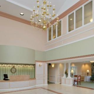 A spacious hotel lobby featuring a grand chandelier and a reception desk.