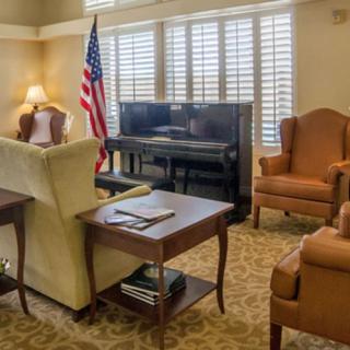 A cozy living room with a piano, armchairs, and an American flag.