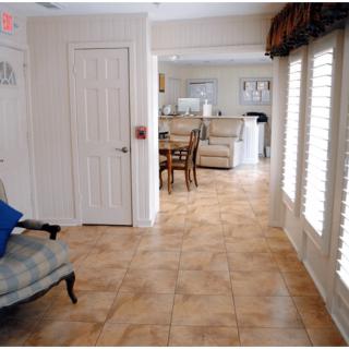 A cozy living room area with tiled floors, comfortable seating, and ample natural light from large windows.