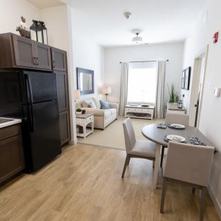 A modern apartment interior featuring a kitchen, dining area, and living room with contemporary furnishings.