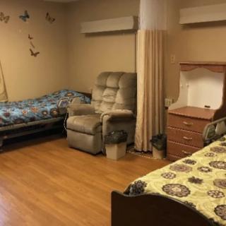A cozy shared bedroom with two beds, a recliner chair, and butterfly wall decorations.