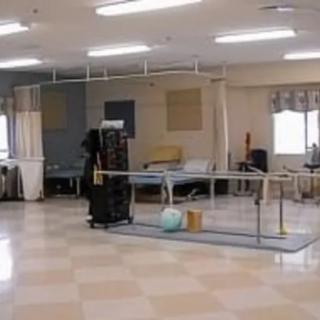 A rehabilitation room with exercise equipment and parallel bars.