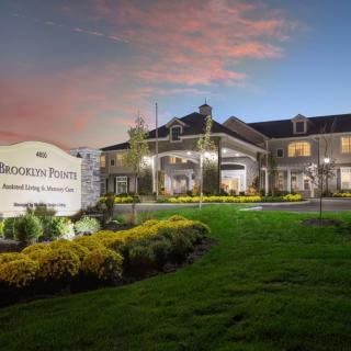 A beautifully lit building at dusk with well-manicured landscaping and a prominent sign in the foreground.