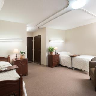 A spacious hospital room designed for patient comfort, featuring two beds and warm lighting.