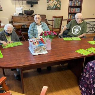 A group of seniors sitting around a table engaged in an activity with a floral centerpiece.