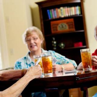 A group of seniors enjoying drinks and conversation at a table indoors.