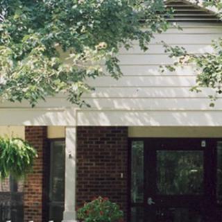 A view of a residential house with trees in the front yard.