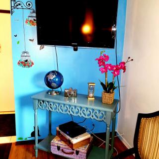 A cozy living room corner featuring a wall-mounted TV, decorative table with a globe, books, and a vibrant orchid.