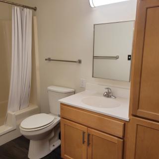 A clean and simple bathroom with a toilet, sink, mirror, and shower.