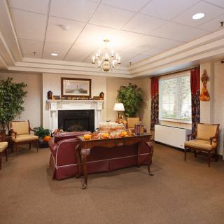A cozy living room with classic decor, featuring a fireplace, sofa, and armchairs.
