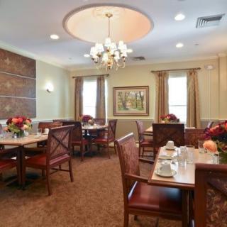 A well-decorated dining room with a chandelier, tables set for meals, and elegant decor.