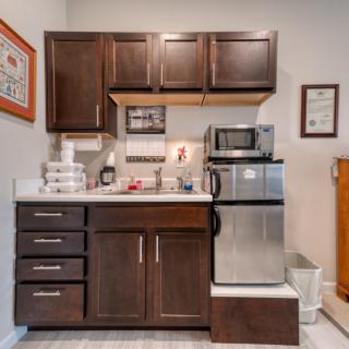 Compact kitchenette with dark brown cabinets, a mini fridge, and a microwave.