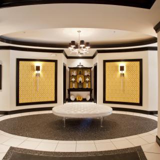 A modern and elegant lobby featuring symmetrical design with a central seating area and decorative lighting.