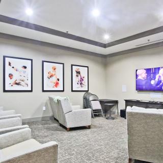 A modern conference room with comfortable seating and a large screen, decorated with contemporary artwork.