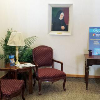 A cozy waiting room with chairs, a lamp, and a portrait on the wall.