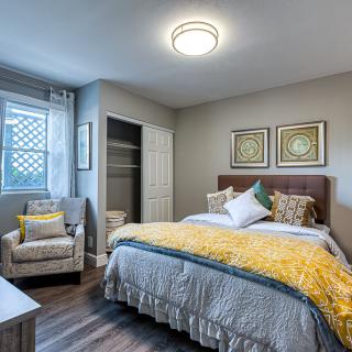 A modern and cozy bedroom featuring stylish decor with a comfortable bed, an armchair, and framed artwork.
