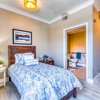 A cozy bedroom with a single bed, nightstand, and an attached bathroom.
