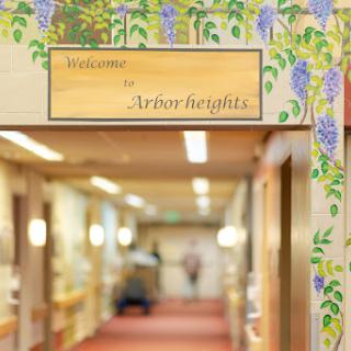 A welcoming sign for Arbor Heights, adorned with decorative floral motifs, inviting visitors into the comforting interior space.