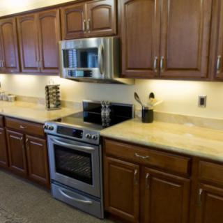 A modern kitchen with wooden cabinets, a stainless steel stove, and a microwave.