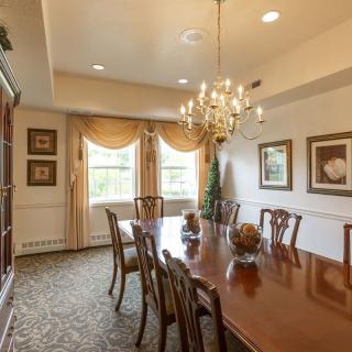 A traditional dining room with a large wooden table, elegant chandelier, and classic decor.
