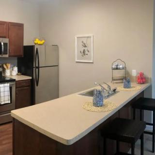 A modern apartment kitchen with a clean countertop and bar stools.
