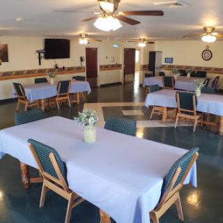 A spacious dining area featuring neatly arranged tables with blue tablecloths.