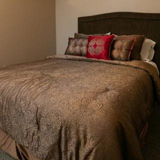 A beautifully made bed with a decorative throw and pillows, inviting a sense of comfort and relaxation.