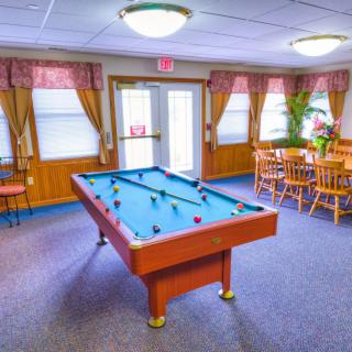 A cozy game room featuring a pool table and wooden furniture.