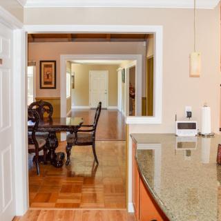 A view from the kitchen into a dining area with wooden flooring and a stylish table.