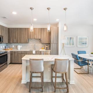 A modern kitchen with wood cabinets and a cozy dining area.
