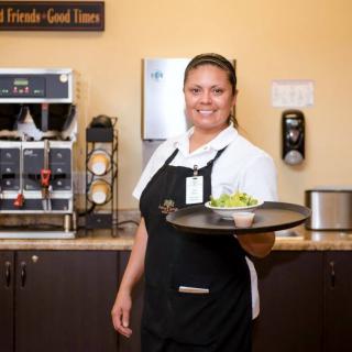 A waitress in uniform holding a tray with food at a restaurant.