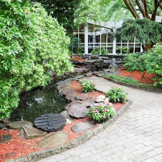 A serene garden featuring a winding pathway, lush greenery, and a tranquil water feature.